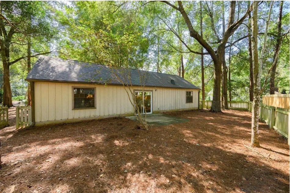 Backyard of the L-shaped ranch home among mature trees in Gainesville
