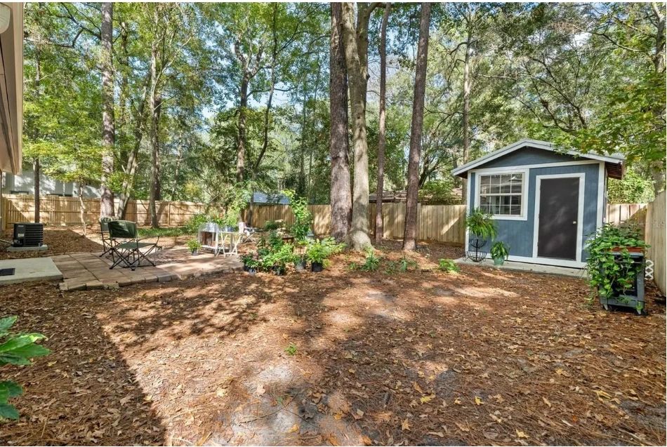Wooded backyard lot of the blue-gray single-story Gainesville home